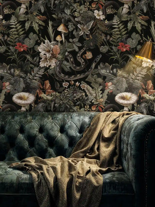 Dark floral wallpaper with woodland creatures shown in moody living room with velvet sofa and brass lamp