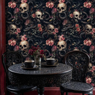 Dark gothic wallpaper featuring skulls and snakes with ornate bistro table and decorative chairs