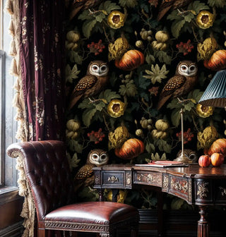 Dark owl botanical wallpaper with pumpkins, shown with tufted leather chair and carved desk