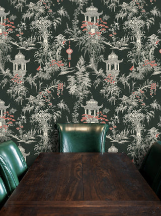 Dark pagoda chinoiserie wallpaper with tropical foliage and red accents, behind green leather dining chairs