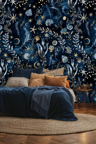 Deep blue marine wallpaper with shells, starfish and celestial elements, displayed in modern bedroom setting