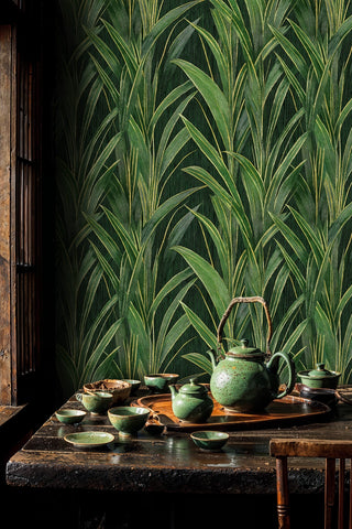 Deep green grass blade wallpaper with gold details behind a rustic table with green ceramic tea set