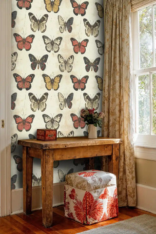 Detailed butterfly specimen wallpaper in antique writing desk area with floral upholstered stool