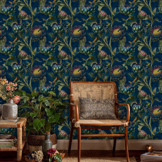 Detailed view of hummingbird wallpaper in navy and green, shown with a rattan chair
