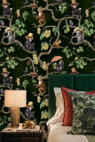 Detailed view of vineyard monkey wallpaper with deep green and gold vines by velvet headboard