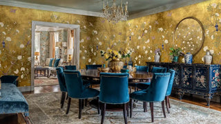 Elegant bird and bloom wall mural in golden tones shown in dining room with navy blue velvet chairs