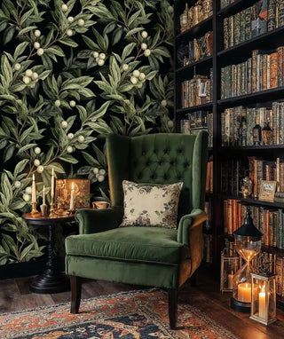Elegant botanical berry wallpaper in home library setting with green velvet armchair and vintage bookshelves
