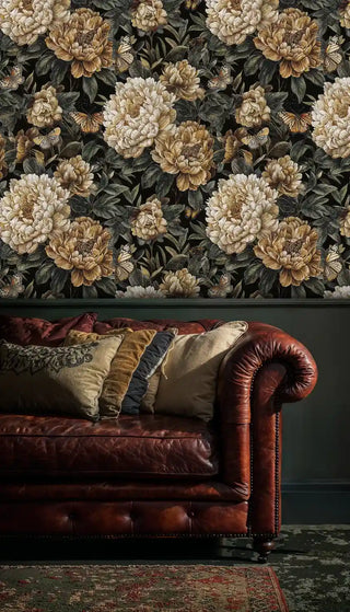 Elegant botanical wallpaper with golden peonies, shown in classic living room with cognac leather Chesterfield sofa