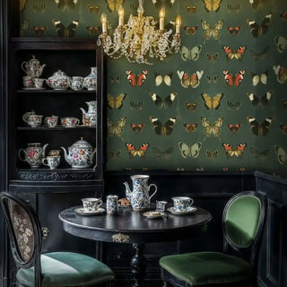 Elegant butterfly wallpaper in a formal dining nook featuring a black china cabinet and a hanging crystal chandelier.