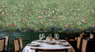 Elegant chinoiserie wallpaper featuring delicate blossoms and rocks, in dining room with green wainscoting