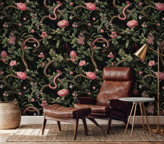 Elegant snake and floral wallpaper in rich black and pink, shown in refined living room with leather armchair