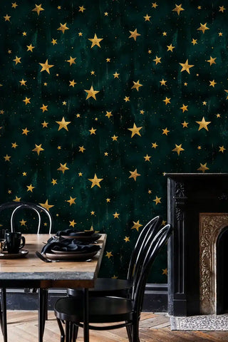 Emerald celestial wallpaper featuring scattered gold stars, shown in dining room with ornate fireplace