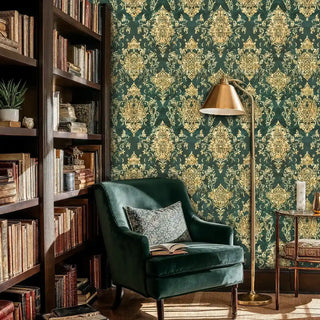 Emerald damask wallpaper with gold ornate patterns in a study with wooden bookshelves and green chair