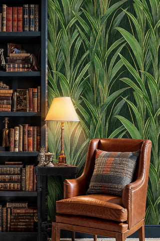 Emerald grass leaf wallpaper in a moody library setting with leather wingback chair and vintage bookshelves