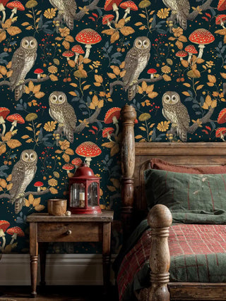 Enchanted forest wallpaper with owls and red mushrooms on teal, shown in bedroom with wooden nightstand