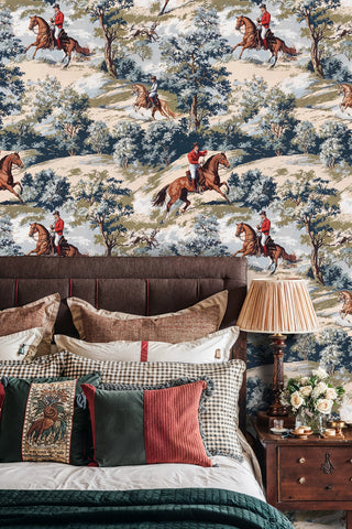 Equestrian scenic wallpaper with galloping horses and trees, beige and blue palette, in a bedroom with bedside lamp