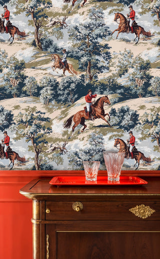 Equestrian scenic wallpaper with riders on horseback, trees and rolling hills, blue beige style, above a red tray and dresser