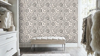 Esoteric pattern wallpaper in beige and black shown in luxury bedroom with tufted bench