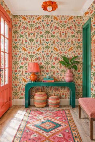 Exotic animal wallpaper with leopards, elephants and palms, coral and green tones, in an entry with console table