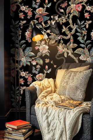 Exotic animal wallpaper with monkeys and botanical elements displayed in cozy reading nook with brass floor lamp