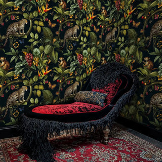 Exotic leopard wallpaper with jungle motifs, shown in dramatic room with red and black fringed chaise lounge