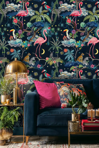 Exotic safari wallpaper featuring flamingos, zebras and tropical foliage on navy, shown in modern living room with gold lamp