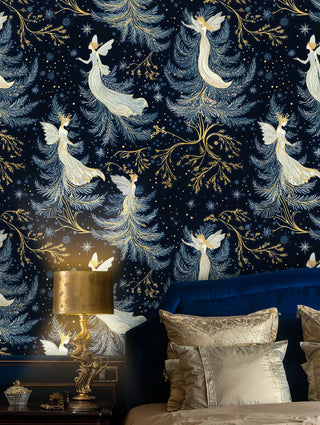 Fairy wallpaper with celestial figures, gold branches and stars in navy, shown with a gold bedside lamp and bed