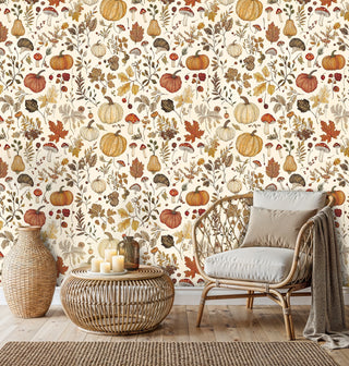 Fall pumpkin and mushroom wallpaper in warm orange and cream tones, in a boho living room with rattan chair and candles