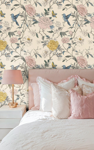 Floral wallpaper with bluebirds and lush peonies on cream, in a pink bedroom with gold lamp