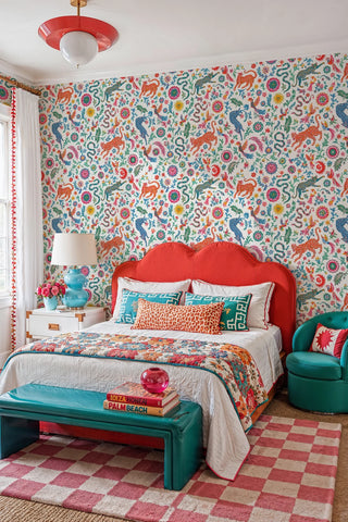Folk art leopard and phoenix wallpaper in vivid colors on white, in a bold bedroom with red upholstered headboard