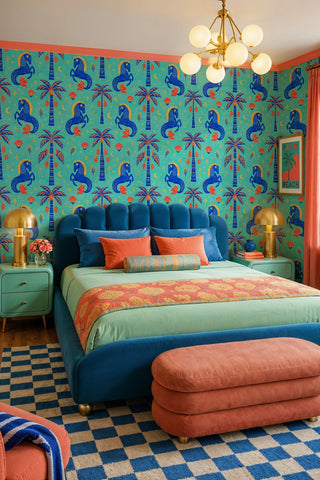 Folk horse and palm tree wallpaper in turquoise and blue in a vibrant bedroom with velvet bed and gold lamps