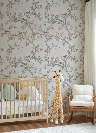 Garden birds wallpaper with flowering branches and butterflies in soft pastels, featured in nursery with wooden crib and giraffe toy