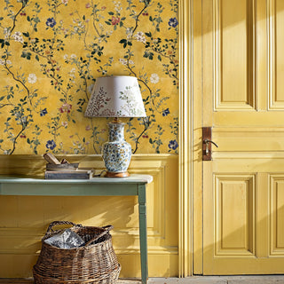 Gold floral branch wallpaper with white and blue blooms, displayed in a sunny entryway with wicker basket and painted console