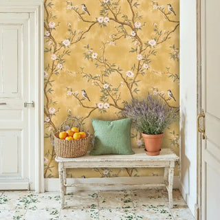 Golden chinoiserie bird wallpaper with pink flowers, displayed in charming entryway with white wooden bench