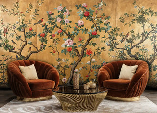 Golden chinoiserie wallpaper featuring songbirds and blooms, displayed in luxurious living room with velvet armchairs