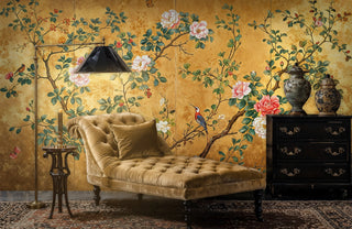 Golden chinoiserie wallpaper featuring songbirds and roses in elegant living room with tufted chaise lounge