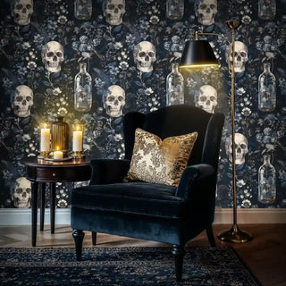 Gothic floral wallpaper with skulls and glass vessels, styled in cozy reading nook with velvet armchair