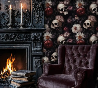 Gothic skull and floral wallpaper in a dark room with a velvet chair beside an ornate, roaring black fireplace.