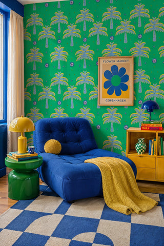 Green embroidered palm wallpaper with folk flowers in a cozy reading nook with blue chaise lounge