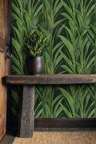 Green grass blade wallpaper with gold veining on dark background, in a rustic entryway with wooden bench and vase