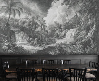 Grey tropical landscape wall mural with palm trees and river, shown in an elegant dining room with dark wood chairs and paneling