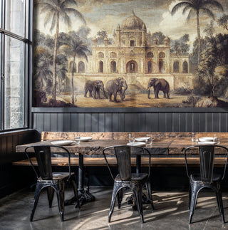 Indian elephant palace wall mural in warm vintage tones, in an industrial cafe with rustic wood table and metal chairs