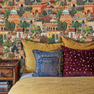 Indian palace garden wallpaper with palace architecture and tropical foliage in cozy bedroom with mustard bedding