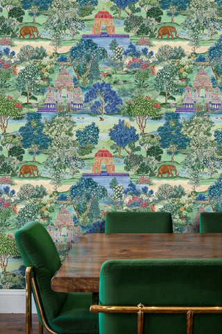 Indian pavilion and elephant wallpaper in rich greens and blues, shown in a modern dining room with green velvet chairs