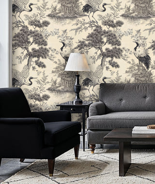 Ink-style crane toile wallpaper with pavilions on cream ground, in a sitting room with black armchair and grey sofa