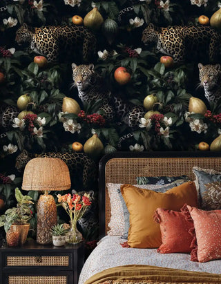 Jungle leopard wallpaper featuring big cats and botanical elements, displayed in boho bedroom with orange pillows