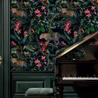 Jungle wallpaper with leopards, lush leaves and pink orchids on dark, shown beside a black grand piano and green paneling
