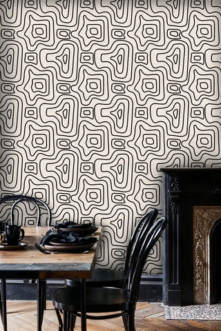 Labyrinth design wallpaper in black and cream shown in dining room with ornate fireplace