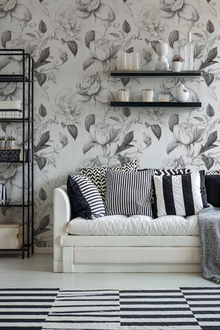 Large-scale floral wallpaper in grey tones, shown in modern living space with black shelving unit