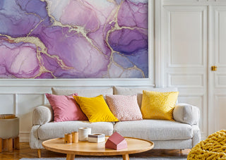 Lavender ink marble wall mural with gold details in a living room with grey sofa and yellow pillows